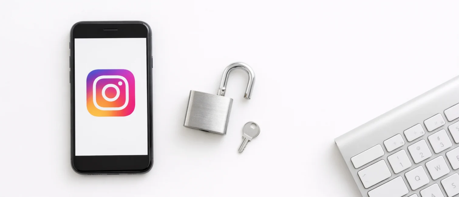 Smartphone mit Instagram-Icon, geöffnetes Vorhängeschloss und Tastatur auf hellem, minimalistischem Hintergrund.