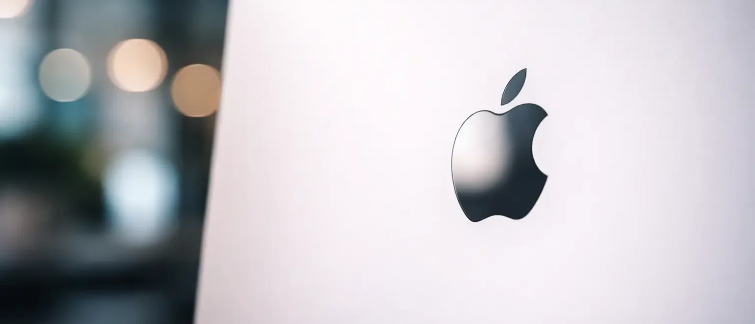 Minimalistische, moderne Darstellung eines silbernen Apple-ähnlichen Laptops auf hellem Hintergrund, mittig leicht rechts platziert, mit dezentem Licht und cleanem Tech-Charakter.