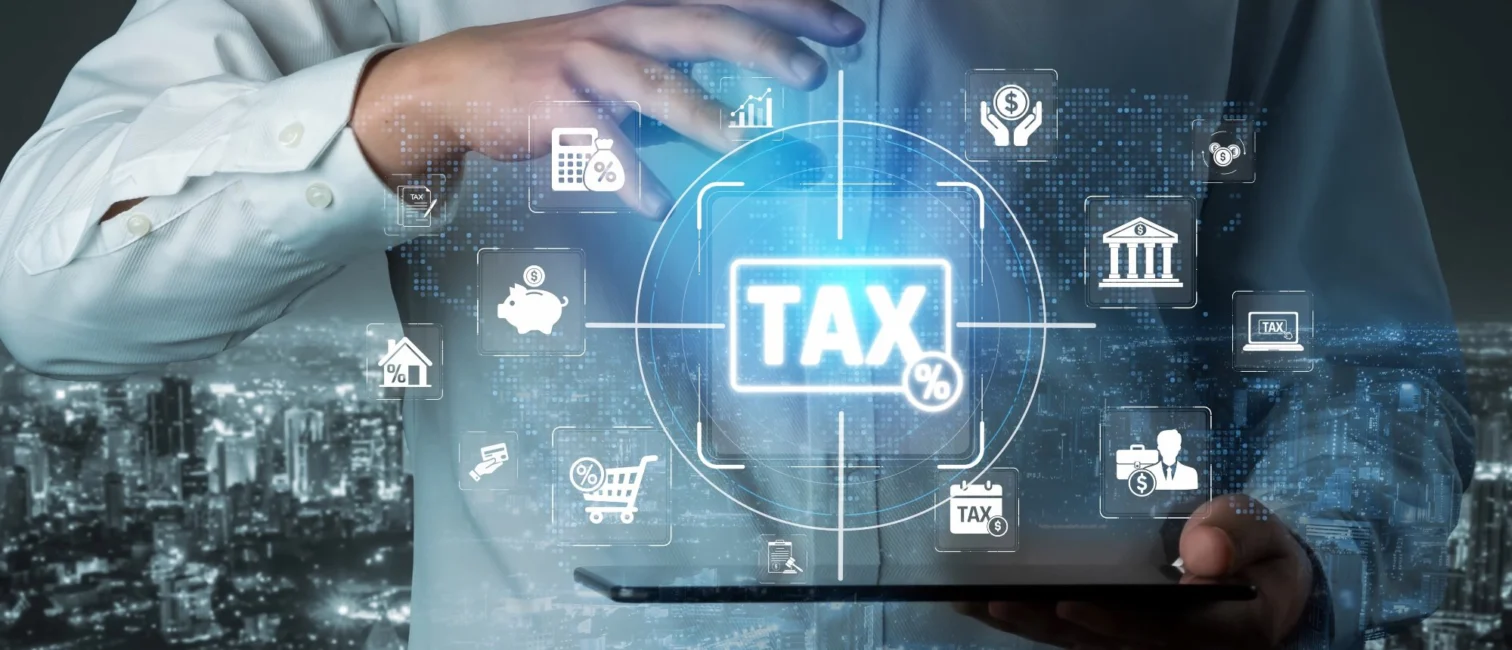 Hand über einem Tablet mit leuchtendem Tax-Symbol und Finanz-Icons