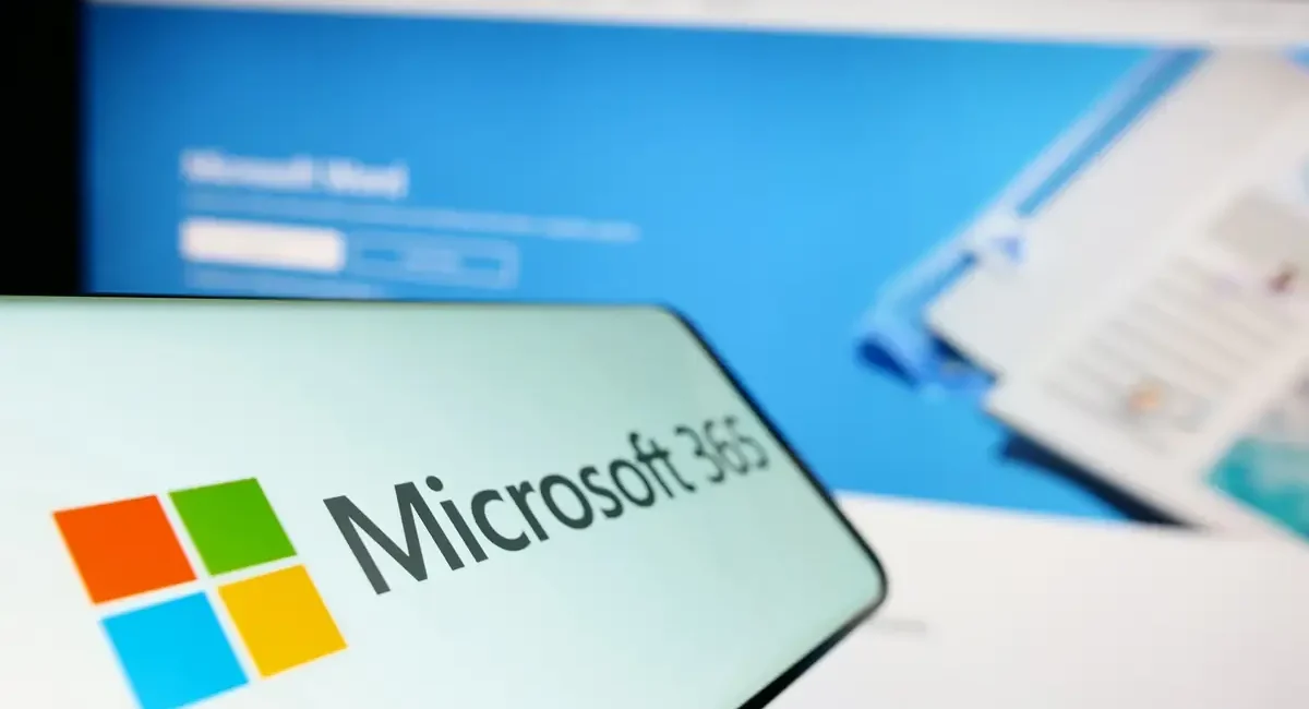 Microsoft-365-Logo auf einem Smartphone vor einem Bildschirm